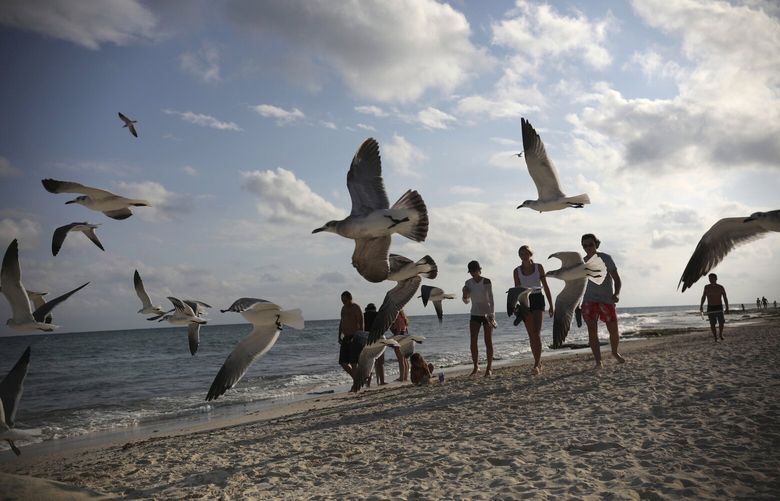 Tourists stroll on the shore of Xcalacoco beach in Playa del Carmen, Quintana Roo state, Mexico, Wednesday, Jan. 6, 2021, amid the new coronavirus pandemic. Quintana Roo, the country’s tourism crown jewel, home to Cancun, the Riviera Maya and Tulum, received more than 900,000 tourists spanning the end of 2020 and the start of 2021. (AP Photo/Emilio Espejel)