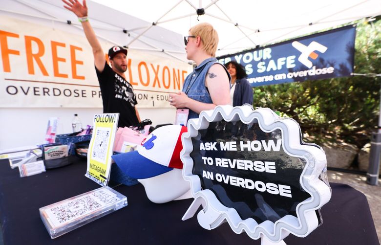 William Perry, left, a director with the nonprofit This Must Be the Place, and volunteer Andi Wilson give out free generic versions of Naloxone kits and training on how to use them at the Day In Day Out music festival in Seattle on Saturday, August 12, 2023.