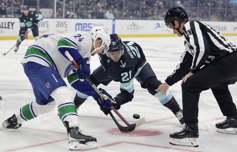Seattle Kraken center Alex Wennberg (21) faces off against Vancouver Canucks center Pius Suter (24) during the first period of a preseason NHL hockey game Thursday, Sept. 28, 2023, in Seattle. (AP Photo/John Froschauer) WAJF106 WAJF106