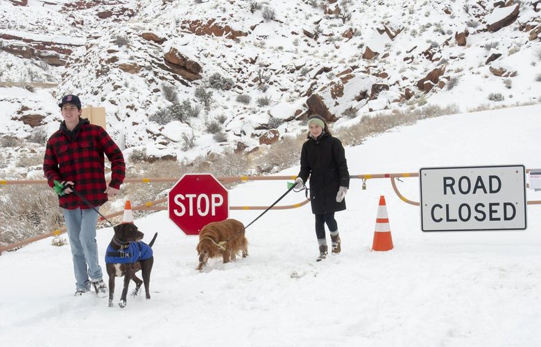 FILE – Parker Smith and Hillary Smith hike along a closed road outside Arches National Park in Utah which is closed due to the partial government shutdown, in January 2019. Arizona’s Grand Canyon National Park and all five national parks in Utah will remain open if the U.S. government shuts down, Sunday, Oct. 1, 2023. Arizona Gov. Katie Hobbs and Utah Gov. Spencer Cox say that the parks are important destinations and local communities depend on dollars from visitors. (Rick Egan/The Salt Lake Tribune via AP, File) UTSAC202 UTSAC202