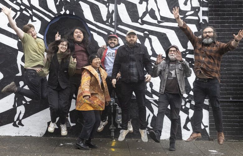 Vera Project Executive Director Ricky Graboski (3rd from right) jumps up with his crew in front of a mural outside of the Black Lodge in Seattle, which is being revamped, Wednesday, September 27, 2023.  The longtime DIY venue Black Lodge is reopening under the guiding arm — and 501(c)(3) — of the Vera Project.  They are working hard to meet the date when the venue will reopen. 225024