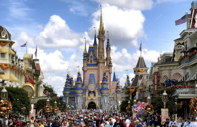 FILE – Crowds fill Main Street USA in front of Cinderella Castle at the Magic Kingdom on the 50th anniversary of Walt Disney World, in Lake Buena Vista, Fla., on Oct. 1, 2021. Facing backlash, Walt Disney World’s governing district will pay a stipend to employees whose free passes and discounts to the theme park resort were eliminated under a policy made by a new district administrator and board members who are allies of Florida Gov. Ron DeSantis. (Joe Burbank/Orlando Sentinel via AP, File) FLORL351 FLORL351