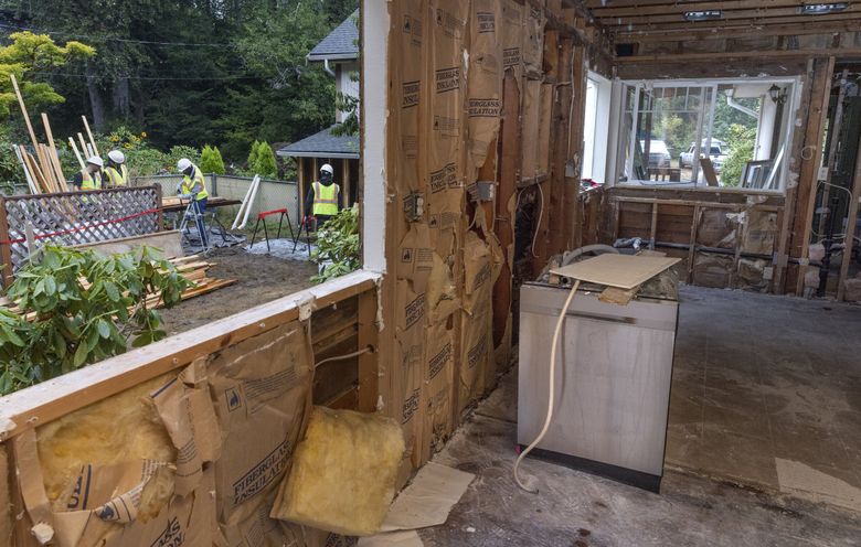 Construction workers and trainees outside remove nails from studs as they recycle material from a home in Maple Valley. (Ellen M. Banner / The Seattle Times)
