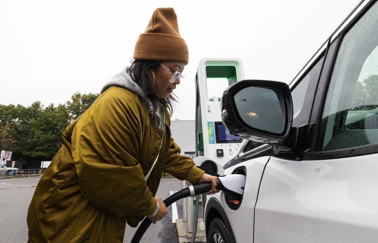 Meesa Pedrozo at a Lower Queen Anne charging station plugs into her EV, Monday, Oct. 9, 2023 in Seattle.