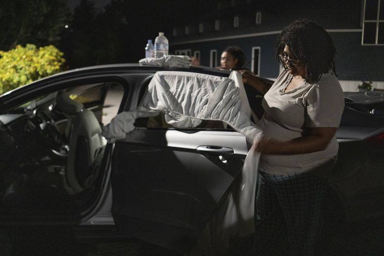 Chrystal Audet and her daughter, Cierra, place sheets on the windows of their car to create privacy in Kirkland, Wash., on Aug. 27. (Ruth Fremson / The New York Times) 