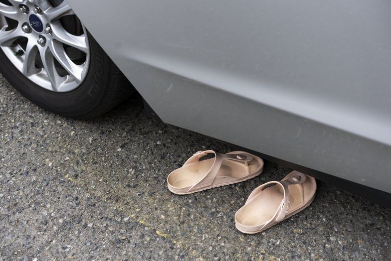 To stretch out in the back seat, Chrystal Audet leaves the car door ajar while she sleeps, and leaves her sandals on the pavement, in case she needs to go to the portable toilet. She&#8217;s at 
a SafePark location at a United Methodist Church in Kirkland, Wash., on Aug. 28. (Ruth Fremson / The New York Times)
