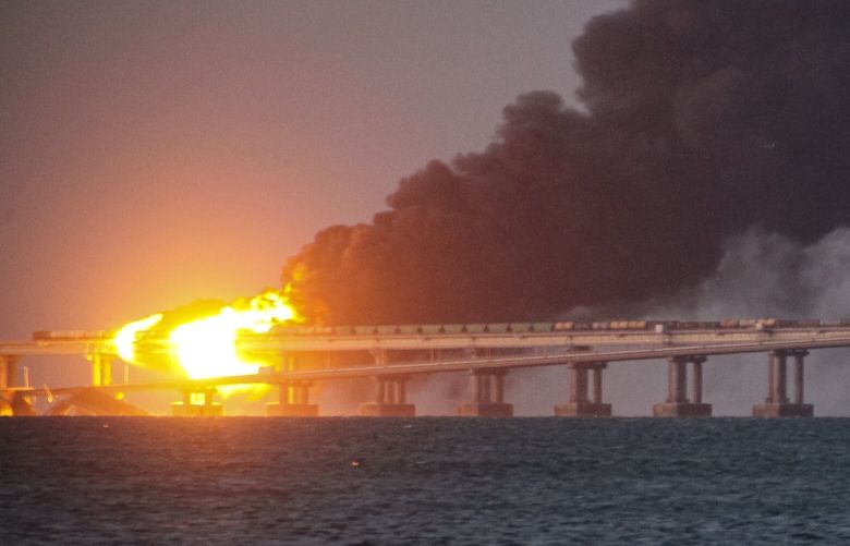 Flame and smoke rise fron Crimean Bridge connecting Russian mainland and Crimean peninsula over the Kerch Strait, in Kerch, Crimea, Saturday, Oct. 8, 2022. (AP Photo)