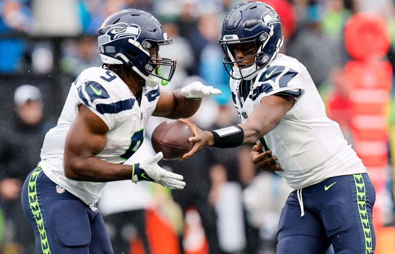 Seattle Seahawks quarterback Geno Smith, right, hands the ball off to running back Kenneth Walker III during the fourth quarter Sunday, Sept. 24, 2023 in Seattle. 225054