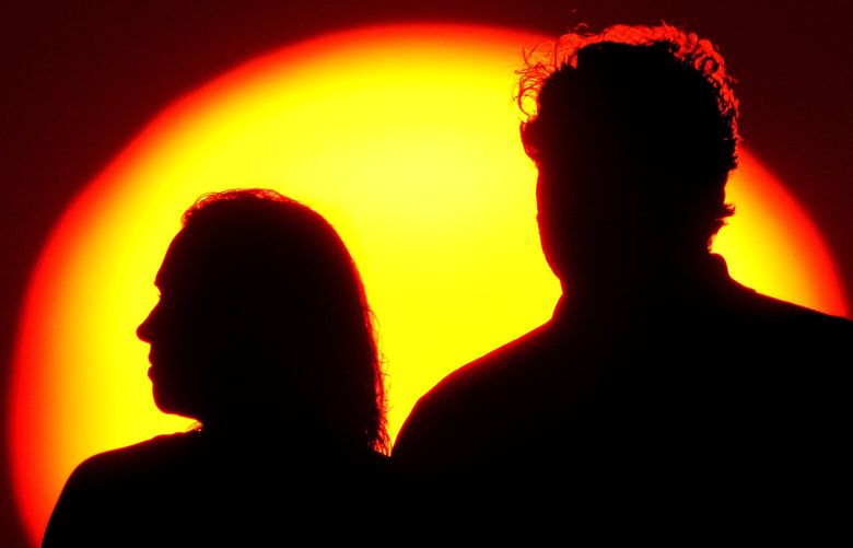 FILE – A couple watches the sun set from a park, July 10, 2021, in Kansas City, Mo. After a spouse dies, the survivor’s financial situation often changes for the worse. Social Security benefits can drop. Tax rates go up (known as the “widow’s penalty”). Pension income may fall or disappear entirely. The longer the survivor lives, the worse their financial position may become. Some survivor penalties can’t be avoided, but good planning can reduce their impact. (AP Photo/Charlie Riedel, File) NYPS205 NYPS205