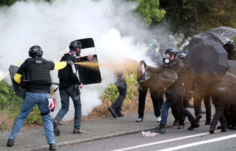Members of the far-right group Proud Boys and anti-fascist protesters spray bear mace at each other during clashes between the politically opposed groups on Sunday, Aug. 22, 2021, in Portland, Ore. (AP Photo/Alex Milan Tracy)