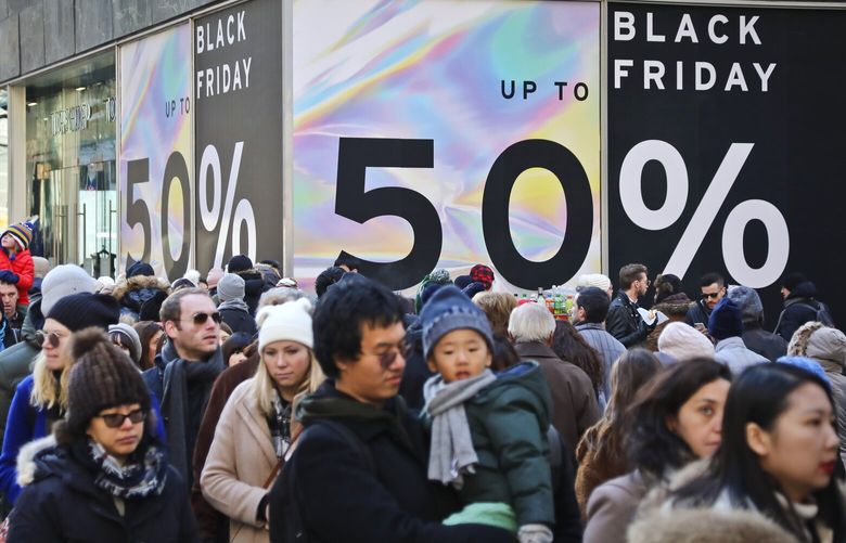 File – Crowds walk past a large store sign displaying a Black Friday discount in midtown Manhattan, Friday, Nov. 23, 2018, in New York. While Black Friday may no longer look like the crowd-filled, in-person mayhem that it was just decades ago — in large part due to the rising dependence on online shopping that was accelerated by the COVID-19 pandemic — the holiday sales event is still slated to attract millions of consumers. (AP Photo/Bebeto Matthews, File) NYPM304 NYPM304