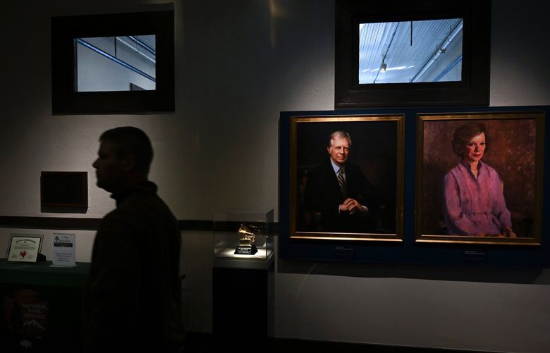 A visitor walks by portraits of former president Jimmy Carter and former first lady Rosalynn Carter in February at the Jimmy Carter National Historical Park Visitor Center in Plains, Ga. MUST CREDIT: Matt McClain/The Washington Post