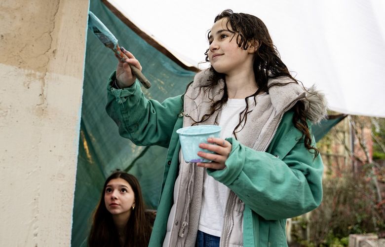 Naomi Wintry, 14, and Hannah Will, 14, paint a mural on a previously vandalized wall Friday, Dec. 1, 2023, at Temple di Hirsch Sinai in Seattle. The mural was vandalized in April and Rabi Daniel Weiner says the mural’s uplifting message is especially needed amid the tension brought by the Israel Hamas war.
