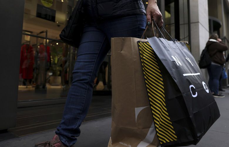 FILE – A shopper carries bags down Fifth Avenue on Nov. 25, 2022, in New York. Making returns will be more difficult this holiday season because more retailers are charging return fees, but there are ways to avoid them. Reviewing stores’ return policies before buying can mean fewer unpleasant surprises later. In some cases, joining a loyalty program can allow shoppers to avoid return fees while also offering access to early sales and exclusive offers. (AP Photo/Julia Nikhinson, File) NYPS205 NYPS205