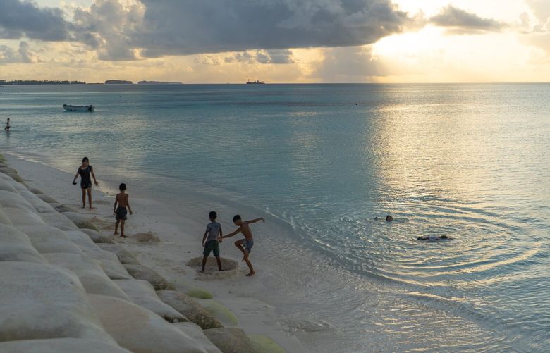 Children play in the Funafuti lagoon in Tuvalu next to a patch of restored land. Until it was recently rebuilt, the area had been washed away by rising seas. MUST CREDIT: Michael Miller/The Washington Post