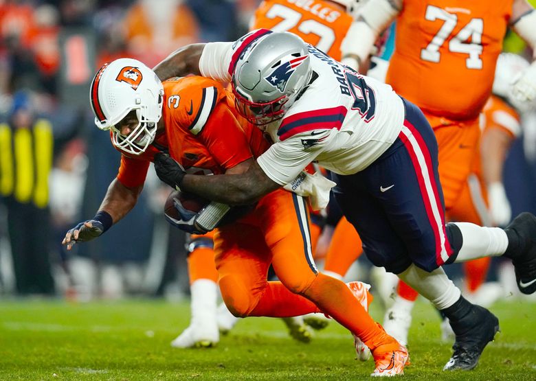 Denver Broncos quarterback Russell Wilson is sacked by New England Patriots defensive tackle Christian Barmore (90) during the second half of an NFL football game against the New England Patriots, Sunday, Dec. 24, 2023, in Denver. (Geneva Heffernan / The Associated Press)