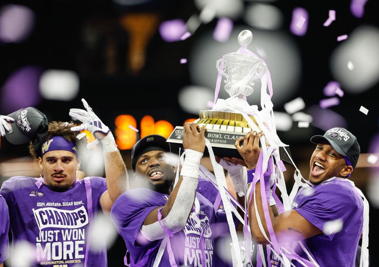 Michael Penix, right, and Edefuan Ulofoshio raise the Sugar Bowl Trophy.  The second-ranked University of Washington Huskies played the third-ranked Texas Longhorns in the Sugar Bowl, the semifinal game of the College Football Playoffs, Monday, January 1, 2024 at the Superdome, in New Orleans, Louisiana. (Dean Rutz / The Seattle Times)