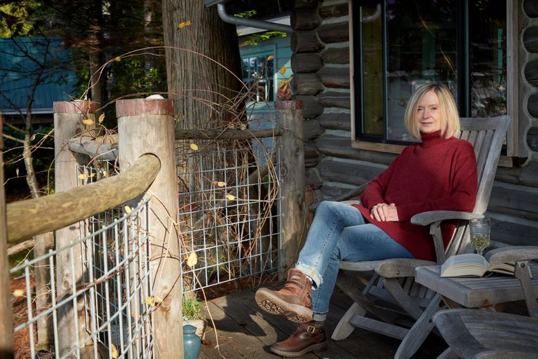 Pam Austin at her log cabin on Guemes Island, off the coast of Washington, Dec. 12, 2023. In 2000, Austin and her now ex-husband bought the little house, which sits on a beachfront lot, as a getaway from their primary home in Seattle. (Moris Moreno / The New York Times)
