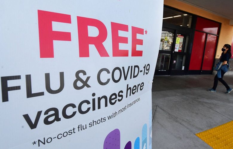 A woman arrives at a CVS pharmacy past a sign about free flu and COVID-19 vaccines on Jan. 14, 2022, in Monterey Park, California. (Frederic J. Brown/AFP/Getty Images/TNS) 100151661W