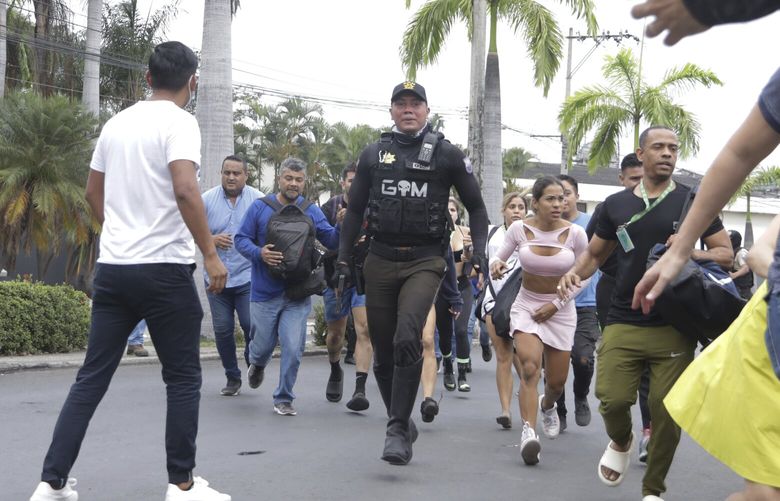 Police evacuate staff from the TC television channel station after a group of armed men broke onto their set during a live broadcast, in Guayaquil, Ecuador, Tuesday, Jan. 9, 2024. The country has seen a series of attacks after the government imposed a state of emergency in the wake of the apparent escape of a powerful gang leader from prison. (AP Photo/Cesar Munoz) DOR114 DOR114