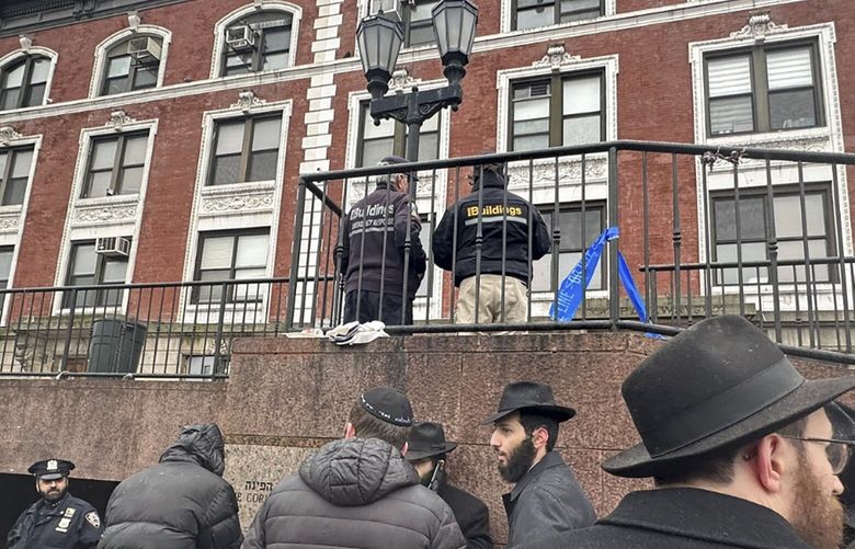 City inspectors and police officers outside the Brooklyn borough, N.Y., headquarters of the Chabad movement, Tuesday, Jan. 9, 2024. The building was evacuated after a tunnel was discovered Monday evening. (AP Photo/Jake Offenhartz) RPJO201 RPJO201