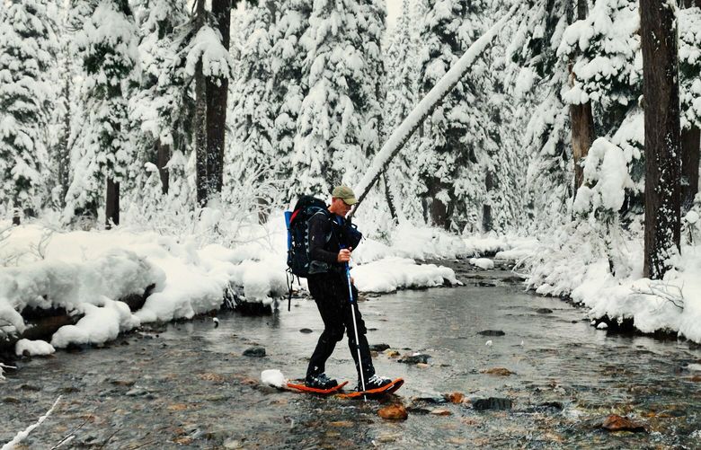 A snowshoer traverses water near Snoqualmie Pass during a Forest Service guided snowshoe tour.