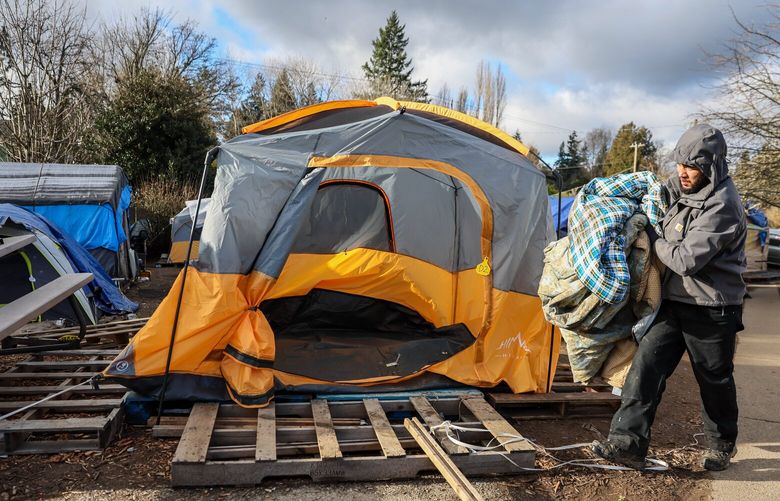 Volunteer Jacob Daniels dismantles a tent Thursday afternoon at the Riverton Park Methodist Church in Tukwila Washington on January 11, 2024. Residents of the encampment were being moved to indoor shelters with incoming cold weather.
