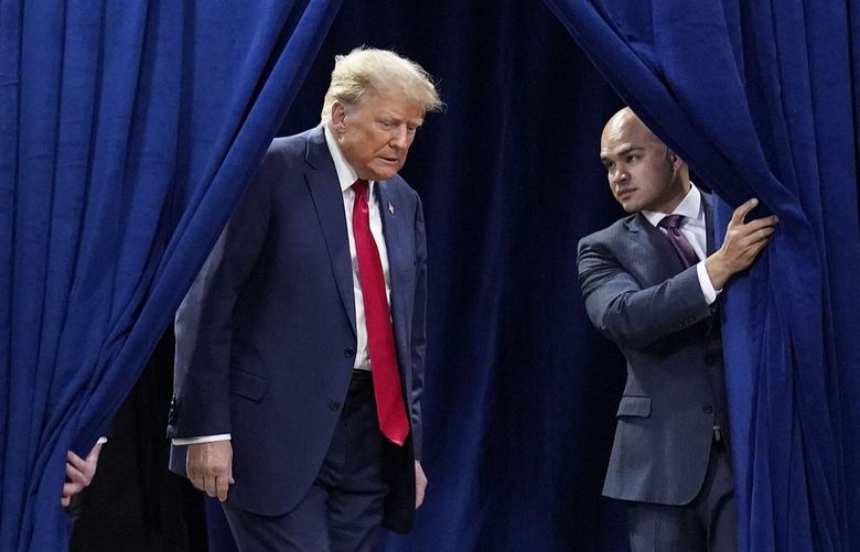 Aide Walt Nauta opens a curtain for former president Donald Trump as he arrives for his caucus night watch party Monday in Des Moines, Iowa. MUST CREDIT: Jabin Botsford/The Washington Post