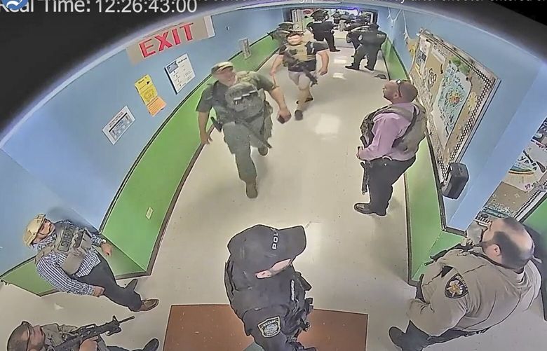 FILE – In this photo from surveillance video provided by the Uvalde Consolidated Independent School District via the Austin American-Statesman, authorities stage in a hallway as they respond to the shooting at Robb Elementary School in Uvalde, Texas, May 24, 2022. The Justice Department says police officials who responded to the deadly school shooting  “demonstrated no urgency” in setting up a command post and failed to treat the killings as an active shooter situation. A Justice Department report released Thursday, Jan. 24, 2024 identifies “cascading failures” in law enforcement’s handling of one of the deadliest massacres at a school in American history. (Uvalde Consolidated Independent School District/Austin American-Statesman via AP, File) TXAUS318 TXAUS318