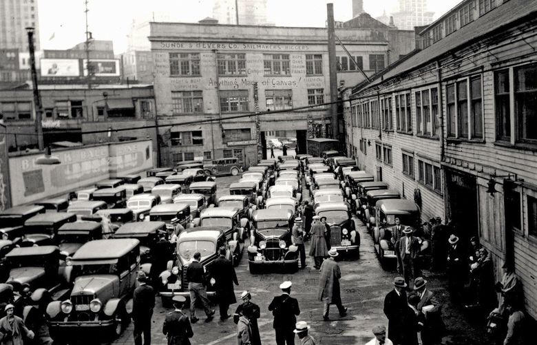 Eight lanes of cars wait at the north side of Colman Dock in this east-looking view near the foot of Marion Street. The 1908 terminal building soon was replaced with the Black Ball Line’s Art Deco terminal. Automotive informant Robert Carney identifies two models from 1936, a Lasalle and a Packard, at the front of the second and fourth lines, respectively, from the right.
