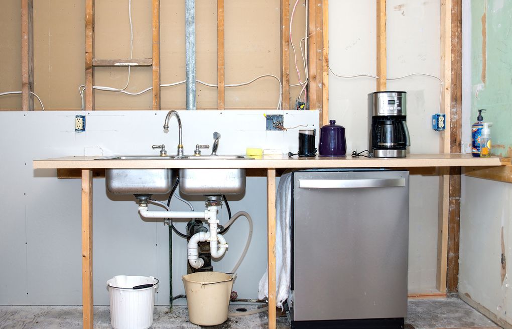 Temporary kitchen setup with sink, appliances, and storage during home remodel