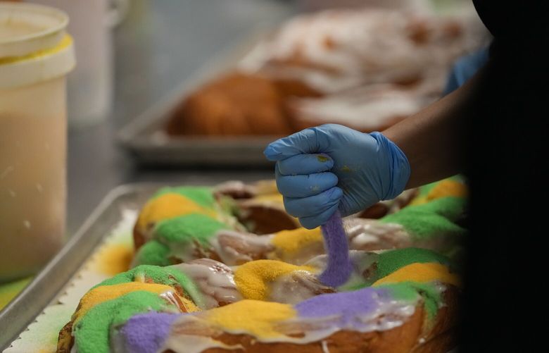 Lawren DiBella sprinkles colored sugar onto king cakes at Haydel’s Bakery in Jefferson Parish, La., Wednesday, Jan. 31, 2024. (AP Photo/Gerald Herbert) LAGH212 LAGH212
