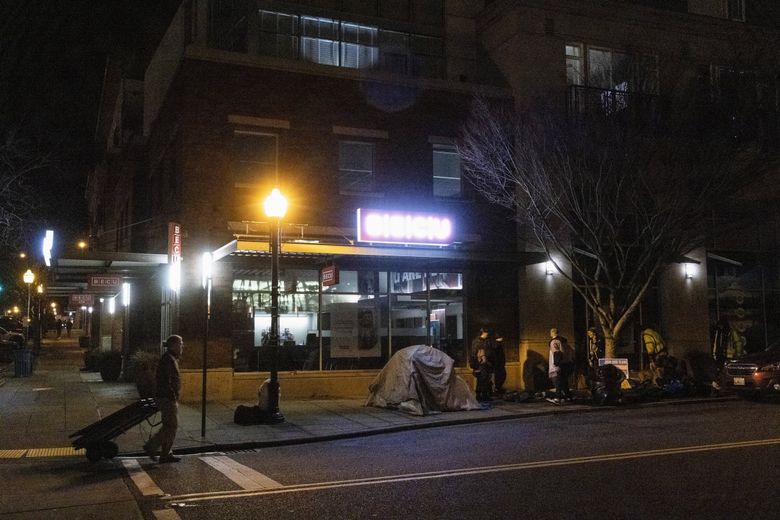 Visible homelessness has returned to downtown Burien as many people have nowhere to go and the city lacks shelter beds to offer. Here, volunteers assist those who wish to sleep in tents in front of BECU. (Ellen M. Banner / The Seattle Times)