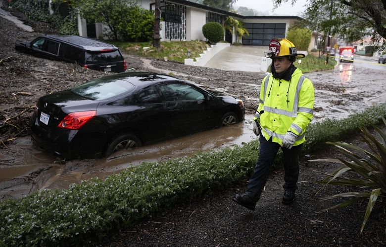 A firefighter walks past vehicles submerged by a mudslide Monday, Feb. 5, 2024, in the Beverly Crest area of Los Angeles. (AP Photo/Marcio Jose Sanchez) CAMS112 CAMS112