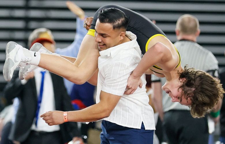 Crew Lambro of Tahoma celebrates his Class 4A 106-pound win as he jumps into the arms of assistant coach Ruben Navejas Saturday, Feb. 17. 2024 in Tacoma. 226125
