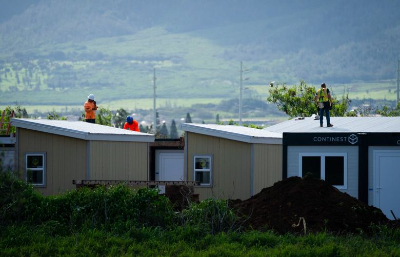 Workers are pictured at the tiny home development. Dozens of the structures have stood on the dusty tract near Maui’s main airport, ready for displaced families to move in. MUST CREDIT: Sarah L. Voisin/The Washington Post