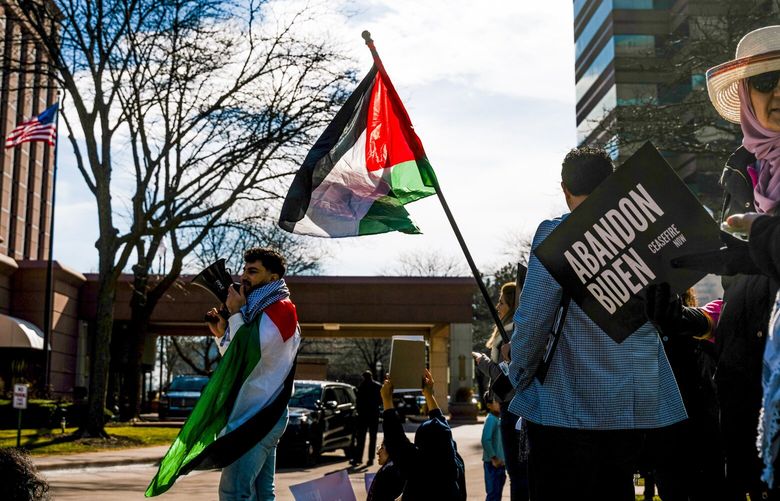 A Palestinian flag is waved during a protest outside The Henry Hotel, where Biden administration officials met with members of Michigan’s Arab American community leaders in closed door meetings, in Dearborn, Mich., on Feb. 8, 2023. Two days before the state’s primary on Tuesday, Feb. 27, 2024, speakers at a gathering in Dearborn pushed voters to cast a ballot for “uncommitted” in objection to President Joe Biden’s handling of the Israel-Hamas war.  (Nick Hagen/The New York Times)