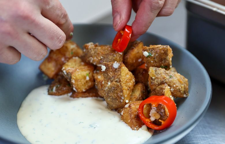 Mitch Mayers, who closed his highly regarded and hugely successful Ballard restaurant, Sawyer, puts the finishing garnishes on his popular brunch potatoes. Photographed at Marx Foods in Seattle. Washington on February 15, 2024. 226152