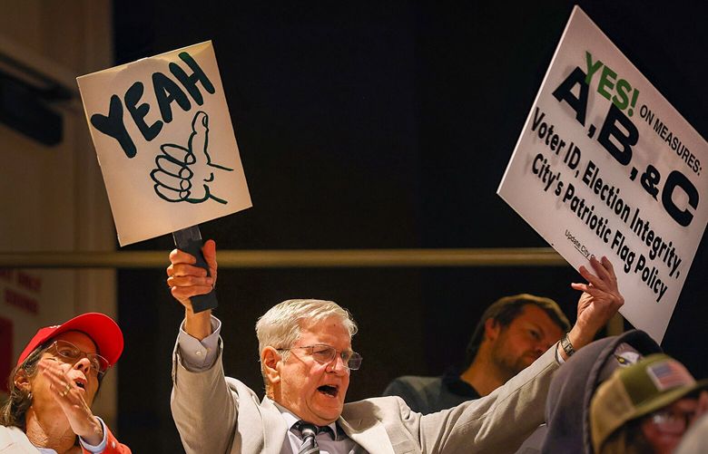 Russell Neal holds up a sign in support of Measures A, B, and C while cheering for a speaker during the public comment session of the Huntington Beach City Council meeting. MUST CREDIT: Rick Loomis for The Washington Post