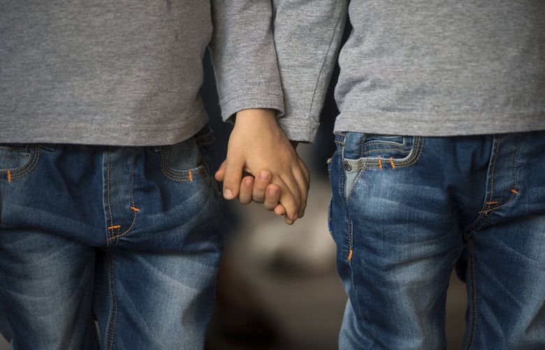 Twin boys hold hands, during an annual gathering of twins, triplets and multiplets in Bucharest, Romania, Saturday, May 31, 2014. The event highlights the issues confronting parents of twins, triplets and multiplets, and pushes for legislation to offer them government support. (AP Photo/Mediafax Foto, Andreea Alexandru) ROMANIA OUT