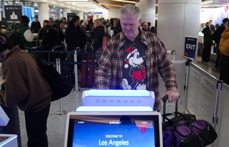 Gary Holm prints his boarding pass using a kiosk at the Delta ticketing counter, Dec. 19, 2022 at Los Angeles International Airport in Los Angeles, Calif. CAJH104