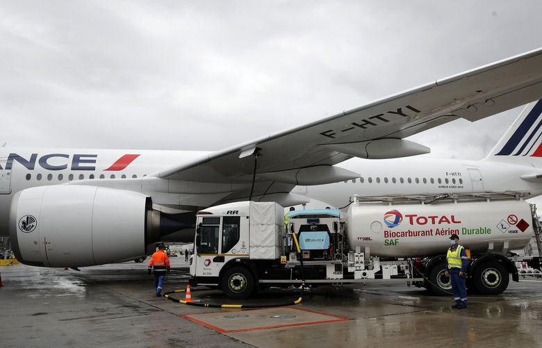 Workers refuel an Airbus A350 with sustainable aviation fuel at Roissy airport, north of Paris, Tuesday, May 18, 2021. Air France-KLM is sending into the air what it calls its first long-haul flight with sustainable aviation fuel Tuesday. The plane is said to be using petroleum mixed with a synthetic jet fuel derived from waste cooking oils. (AP Photo/Christophe Ena)