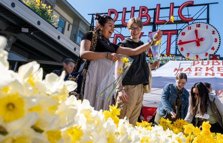 Taylor Williams Guerrero, left, and Jeffrey Pickard browse flowers Tuesday morning during the 27th Annual Daffodil Day at Pike Place Market in Seattle, Washington, on March 19, 2024. 226464