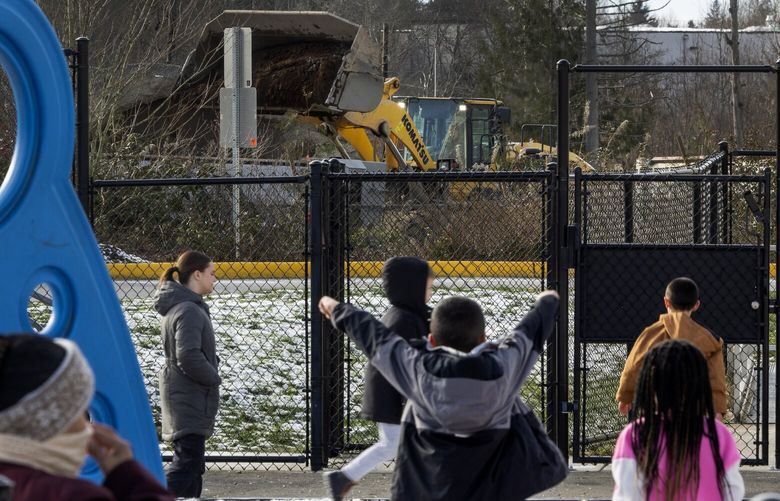 A gravel distribution yard operates without a permit across the street from Fairmount Elementary School as students play at recess, Tuesday, Jan. 16, 2024, in Everett.