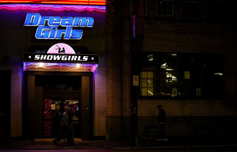 People walk by the Dream Girls at SoDo strip club, Monday, Feb. 5, 2024, in Seattle. Adult dancers are fighting for bills to pass in the state Legislature that would expand statewide protections to workers, like having a security guard at each club, keypad codes to enter dressing rooms and deescalation training. (AP Photo/Lindsey Wasson) WALW111
