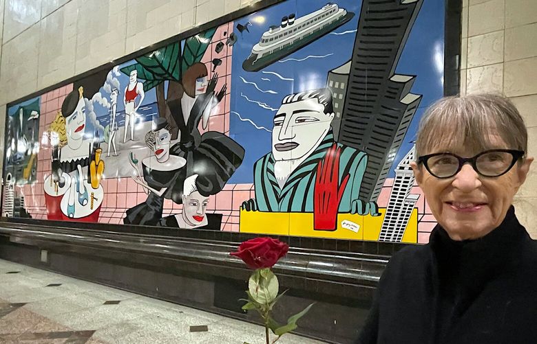 NOW1: Holding a rose to match the red rose she wore at the 1988 dedication ceremony, Gene Gentry McMahon stands in front of her Westlake Station mural in the downtown Sound Transit train tunnel.