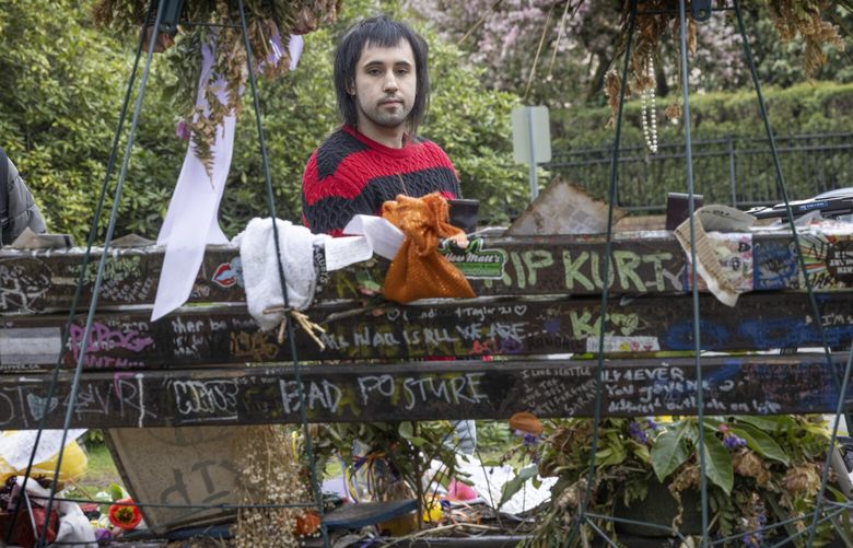Jared Sparks from Portland looks at items placed on a bench in Viretta Park in Seattle left in honor of Kurt Cobain.  Friday, April 5, 2024, is the 30th anniversary of his death.  Sparks wore a black and red sweater he purchased from a thrift store  to the park.  He said they were colors Cobain liked and Cobain liked to shop at thrift stores.  Sparks said that after his visit he was planning to leave the sweater behind on a bench in honor of the rock  star. 226599