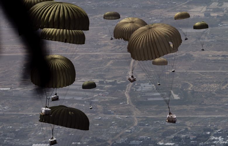 FILE — Parachutes carrying packages begin to descend over Gaza on March 28, 2024. Aid groups and United Nations officials have increasingly warned that the amount of food entering Gaza cannot feed its more than two million people. (Diego Ibarra Sánchez/The New York Times) XNYT0514 XNYT0514