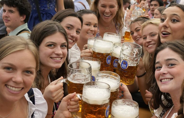 FILE – Women with glasses of beer pose for a photo on day one of the 188th ‘Oktoberfest’ beer festival in Munich, Germany, Saturday, Sept. 16, 2023. The southern German state of Bavaria will ban the smoking of cannabis at public festivals, inside beer gardens, and even at the world’s most popular beer festival, the Oktoberfest. (AP Photo/Matthias Schrader, File) DSOB119 DSOB119