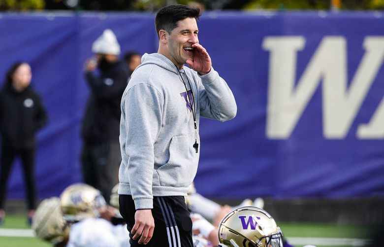 Washington safeties coach Vinne Sunseri walks among his unit as they stretch before practice Tuesday.  Washington held spring practice Tuesday, April 16, 2024. 226664